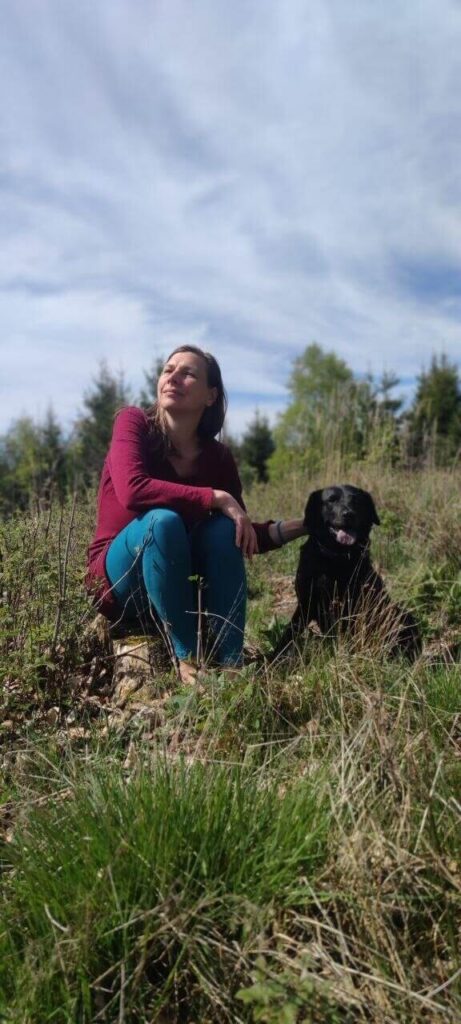 Carla Büscher sitzend in der Natur mit Hund als Bild für TCM, Meridiane und Körperverbindungen